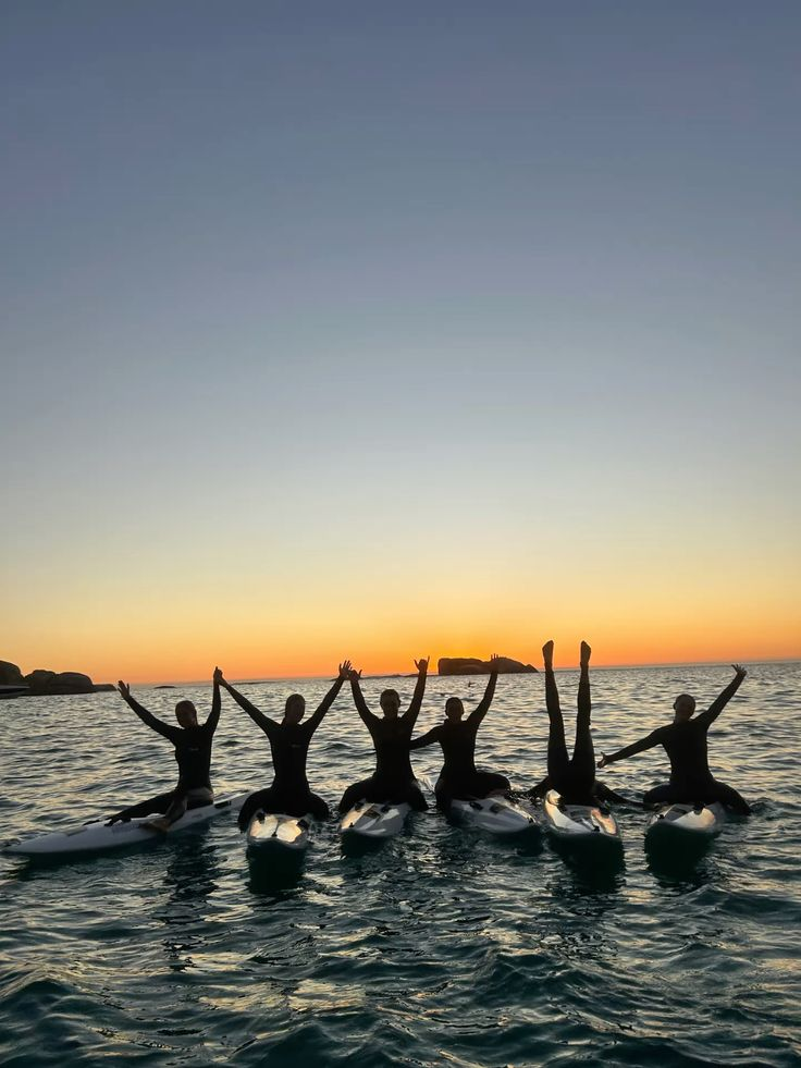 Grupo reunido sobre pranchas no mar ao pôr do sol